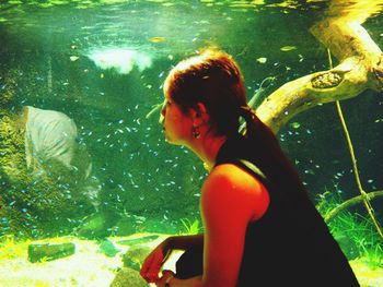 Rear view of woman standing in aquarium
