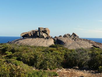 Rock formations by sea against clear sky