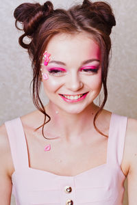 Close-up of female model smiling against wall