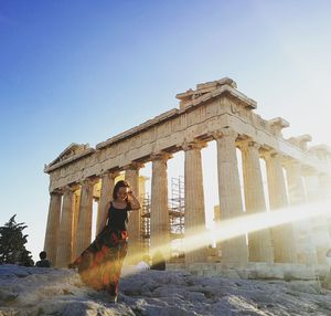 Woman walking by historical building against sky