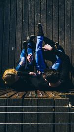 People sitting on wood against fence