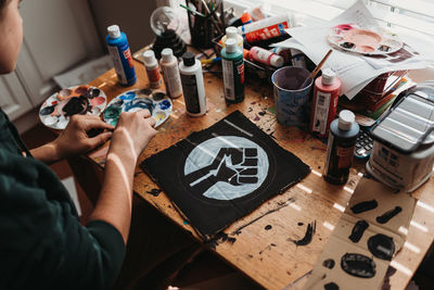 Teen boy painting black lives matter symbol on a protest sign.