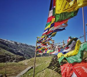 Low angle view of flags hanging on mountain against sky