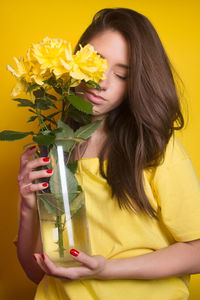 Beautiful young woman holding yellow flower