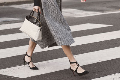 Low section of woman crossing road