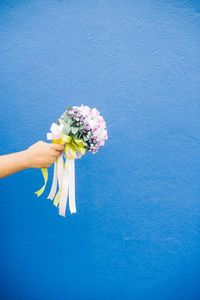 Midsection of man holding flower against blue background