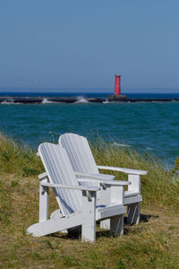 Empty white lawn chairs on the beach