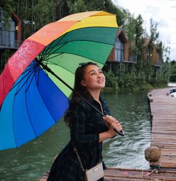 Portrait of young woman with umbrella standing by lake