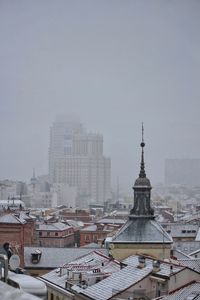 Buildings in city against sky during winter