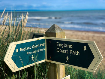 Information sign on beach against sky