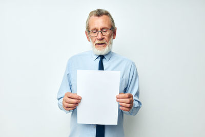 Senior businessman holding paper against white background