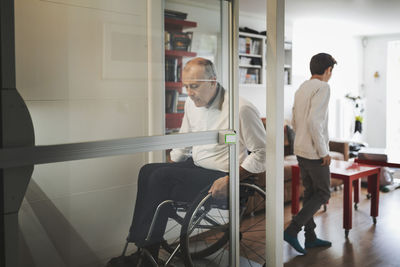 Disabled man in wheelchair exiting lift at home