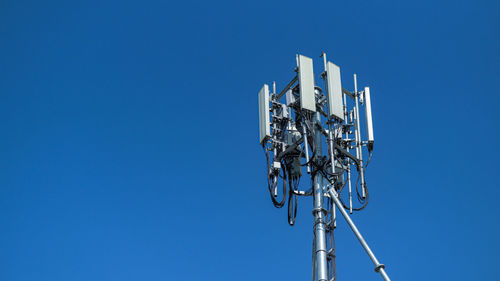 Low angle view of communications tower against clear blue sky