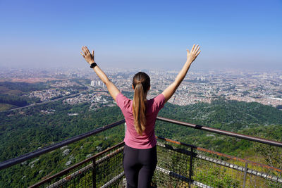 Rear view of woman standing on railing against clear sky