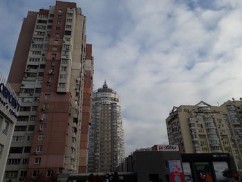 Low angle view of buildings against cloudy sky