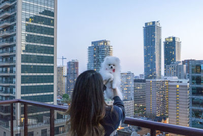 Rear view of girl holding pomeranian in balcony