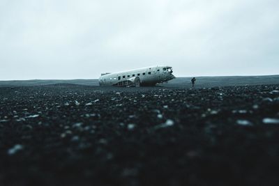 Damaged airplane on sand against sky