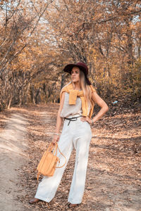 Young woman wearing hat standing against trees