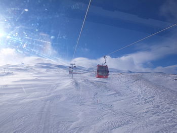 Overhead cable car on snow covered landscape against sky