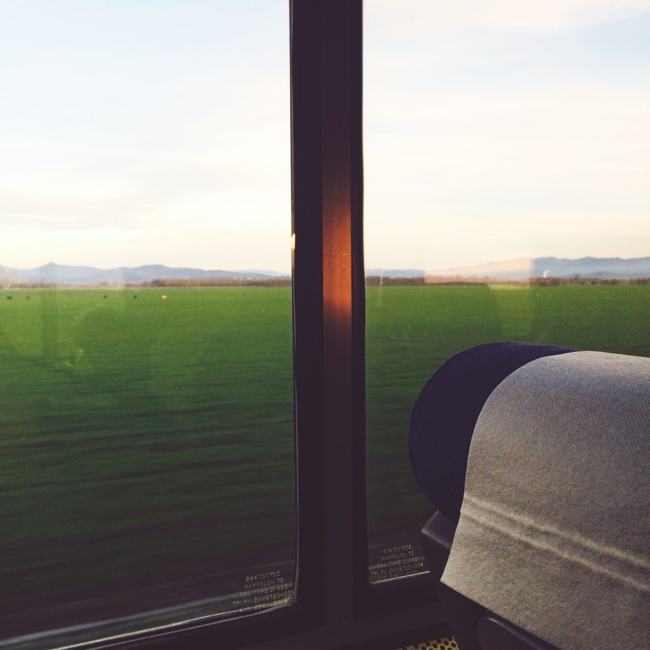 window, landscape, field, sky, glass - material, transparent, indoors, grass, rural scene, agriculture, day, transportation, tranquil scene, green color, no people, cloud, nature, tranquility, cloud - sky, absence