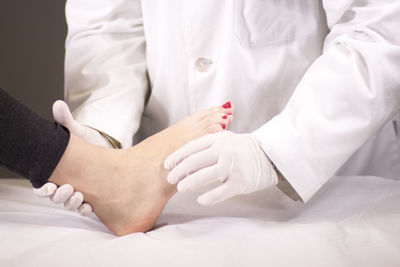 Midsection of doctor examining patient barefoot in hospital