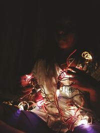 Woman holding illuminated lighting equipment at home