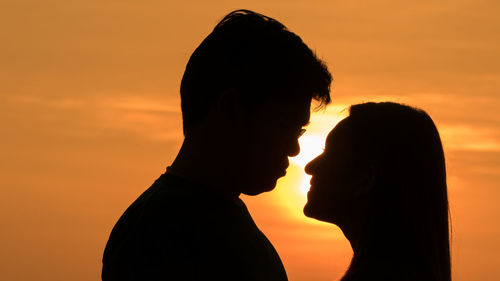 Silhouette couple romancing against sky during sunset