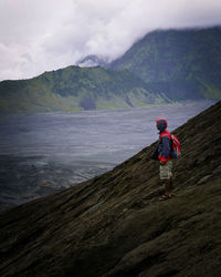 Rear view of man standing on mountain against sky