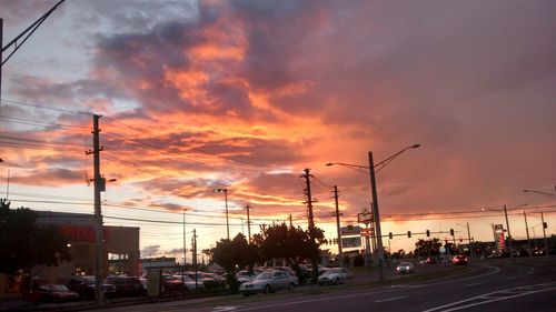 Cars on road against dramatic sky during sunset