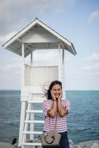 Woman standing on beach looking at sea against sky