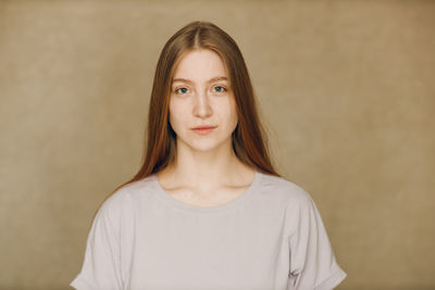 Portrait of young woman standing against wall