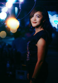 Portrait of a beautiful young woman standing at night