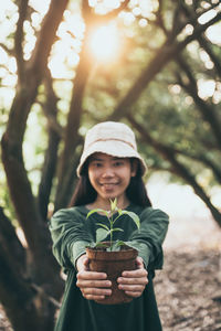 Portrait of smiling young woman standing against plants