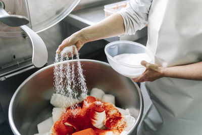 Chef putting ingredient on cheese in machinery at dairy factory