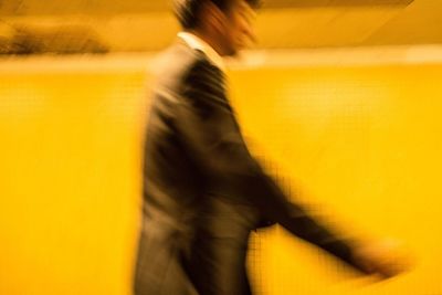 Blurred image of man walking on yellow floor