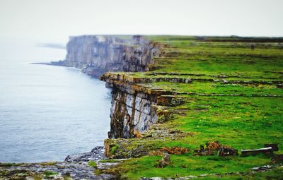 Scenic view of sea by cliff against sky