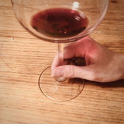 Close-up of hand holding wineglass on table