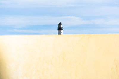 Lighthouse on beach against sky