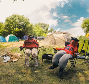 Men sitting in tent on field against sky