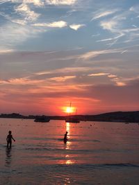 Silhouette people on beach against sky during sunset