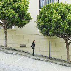 Full length of man walking on footpath by building