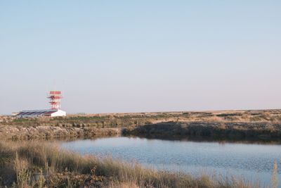 Lighthouse by sea against clear sky