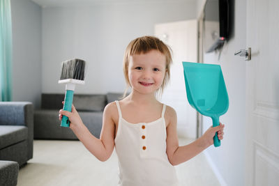  child with blue scoop for garbage and brush sweeping floor helps to clean, development of montessori