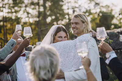 Smiling newlywed couple dancing amidst family and friends at wedding