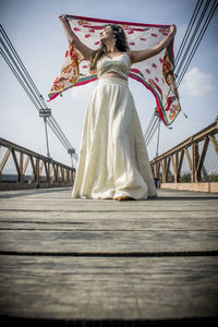 Low angle view of woman with bridge against sky