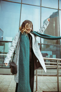 Smiling young woman standing against building