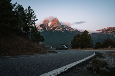 Road by trees against sky during winter