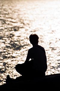 Silhouette of girl sitting on stone wall