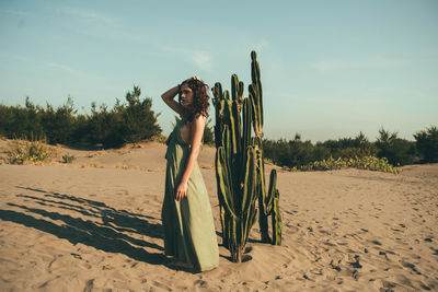 Woman standing on sand at beach against sky