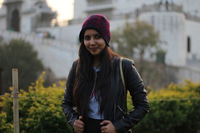 Portrait of smiling young woman standing against building